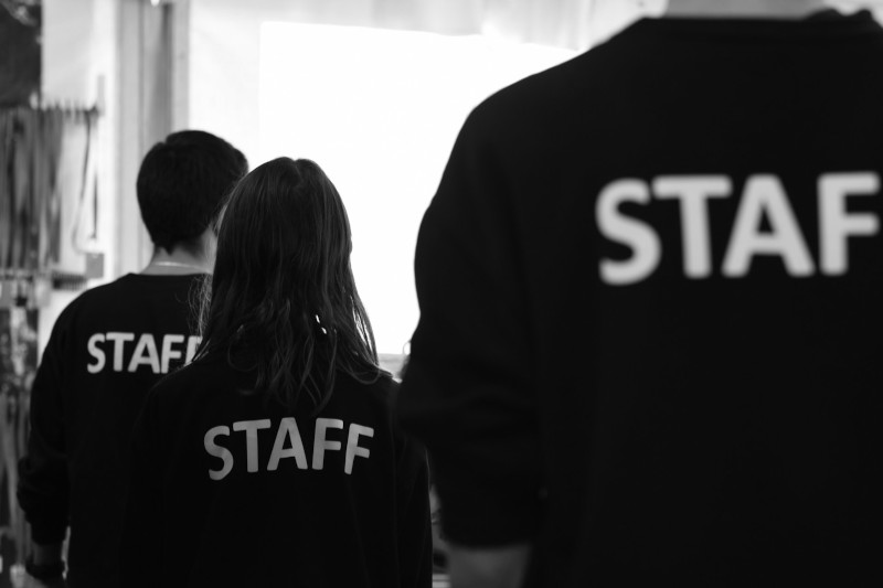 Group of people wearing black t-shirts with staff printed on the back